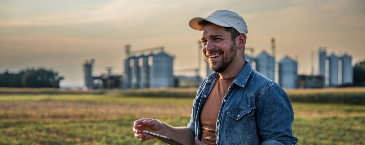 smiling-person-wearing-cap-in-field-with-tablet